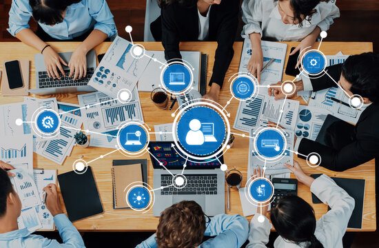 A diverse business team engages in collaborative efforts analyzing data and developing strategies, surrounded by charts, presentations, and innovative technology in an office setting. Amity