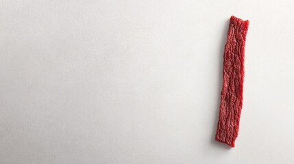 single beef jerky strip with enticing texture rests elegantly on pristine white surface