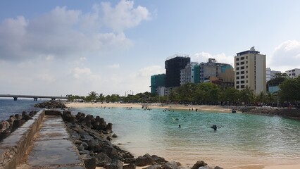 A Busy Beach in the Maldives: People Swimming and Sunbathing