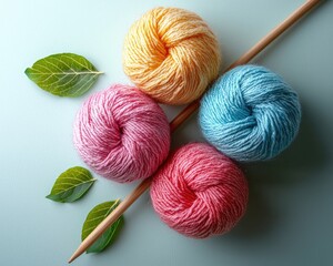 Colorful yarn balls arranged with knitting needles and leaves on a soft surface