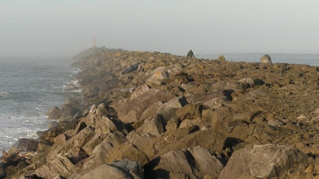 Fisherman walks the jetty in Newport, Oregon