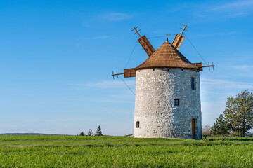 Rustic stone windmill in a grassy field