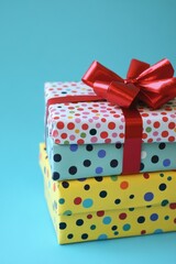 Obraz premium Stacked gifts with colorful polka dots and red ribbon on a blue background creating a cheerful and festive mood perfect for celebration and holiday themes