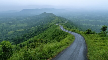 Serene winding road through lush green hills under a misty sky offering a peaceful and scenic journey in nature