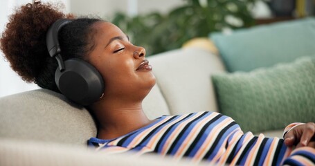Headphones, relax and calm woman on sofa in home listening to music, radio or podcast in living room. Audio tech, rest and female person with streaming album on subscription app in apartment for zen.