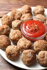 Delicious meatballs with ketchup and spices on wooden table, closeup