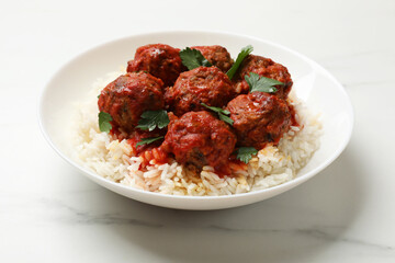 Delicious meatballs with rice, sauce and parsley on white marble table, closeup