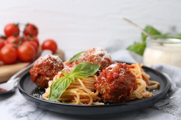 Delicious pasta with meatballs, basil and cheese on white marble table, closeup