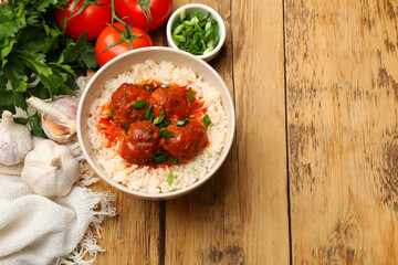 Tasty meatballs with sauce, rice and products on wooden table, flat lay. Space for text