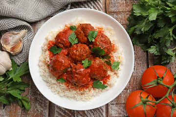 Tasty meatballs with sauce, rice and products on wooden table, flat lay