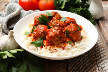 Tasty meatballs with sauce, rice and products on wooden table, closeup