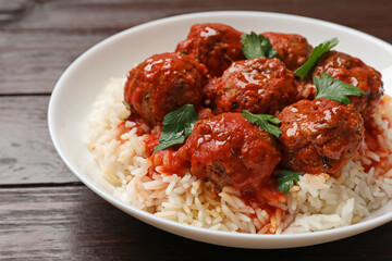 Tasty meatballs with sauce and rice on wooden table, closeup