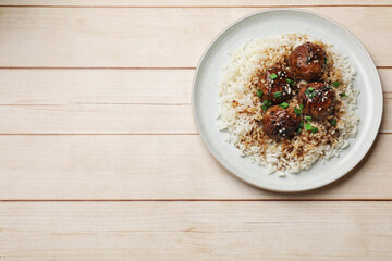 Delicious rice with meatballs, sauce and green onions on white wooden table, top view. Space for text