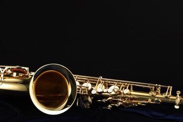 Fototapeta premium Jazz. One beautiful saxophone on dark blue fabric against black background, closeup. Space for text