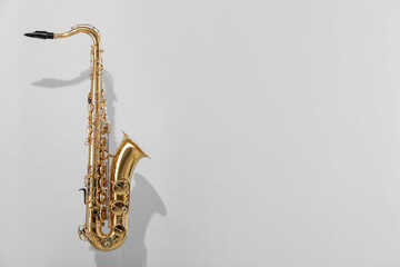 Golden saxophone on light grey background. Space for text