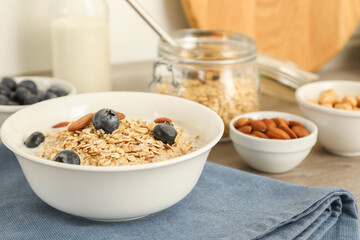 Tasty oatmeal with milk, blueberries and almonds in bowl on table, closeup