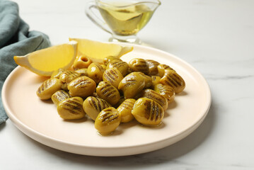 Grilled green olives and lemon wedges on light table, closeup