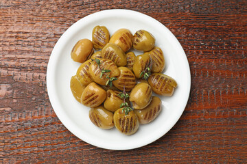 Grilled green olives on wooden table, top view