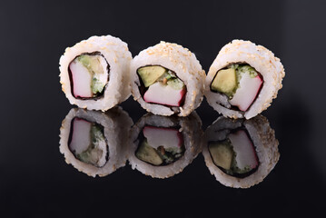 California uramaki sushi rolls reflecting on black background