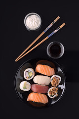 Delicious sushi set served on black plate with soy sauce and mayonnaise