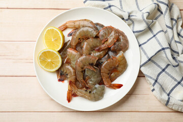 Fresh raw shrimps with lemon on wooden table, top view