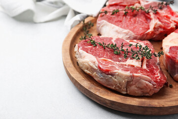 Pieces of raw beef and spices on light grey table, closeup. Space for text