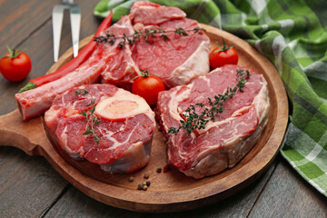 Pieces of raw beef, tomatoes and spices on wooden table, closeup
