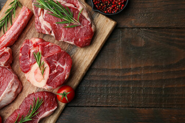 Pieces of raw beef, spices and tomato on wooden table, flat lay. Space for text