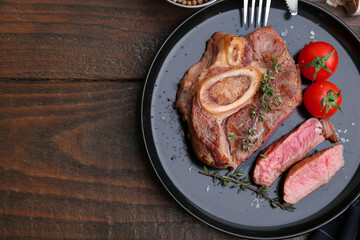 Pieces of delicious beef meat, spices and tomatoes on wooden table, top view. Space for text