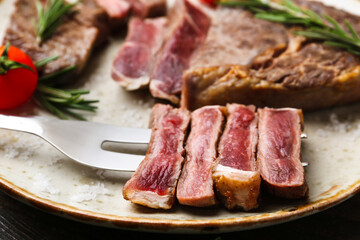 Pieces of delicious beef meat, spices and tomato on table, closeup
