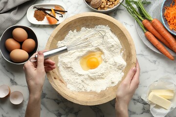 Woman making dough for carrot cake at white marble table with ingredients, top view