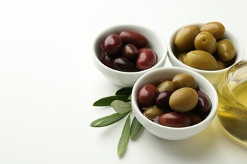 Tasty marinated olives, leaves and oil on white table, closeup. Space for text