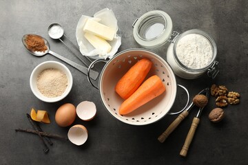 Different ingredients for making carrot cake and kitchenware on dark textured table, flat lay