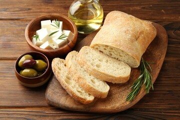 Delicious marinated olives, bread and feta cheese served on wooden table, closeup