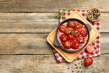Delicious meatballs with tomato sauce in baking dish and spices on wooden table, flat lay. Space for text