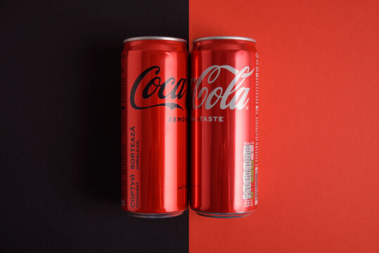 Lviv, Ukraine - March 25, 2025: Iron cans of drink Coca Cola classic and Coca Cola zero sugar on red and black background. Top view