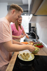 happy couple preparing vegetables and shaping falafels in a bright kitchen enjoying time together while cooking
