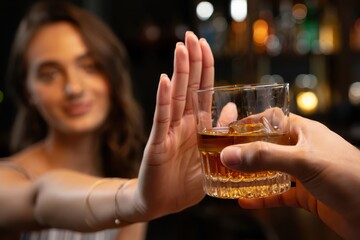 Woman refusing alcohol drink gesture at bar