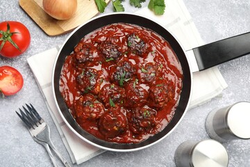 Delicious meatballs with tomato sauce and herbs in served on grey table, flat lay