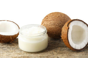 Organic coconut cooking oil in glass jar and fresh fruits on wooden table against white background