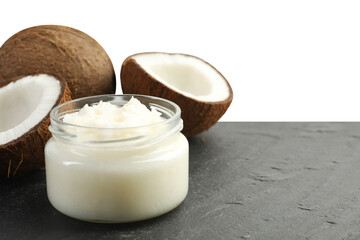 Organic coconut cooking oil in glass jar and fresh fruits on black table against white background