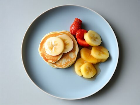 Delicious pancakes served with sliced banana, strawberries and syrup, creating a tempting breakfast presentation