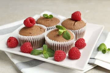 Delicious muffins with raspberries and mint on grey textured table, closeup