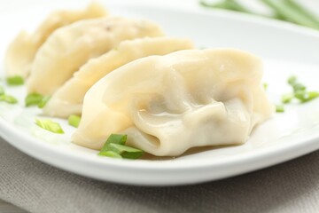 Tasty boiled gyoza (dumplings) with green onion on table, closeup
