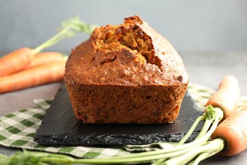 Tasty carrot cake and vegetables on grey table, closeup