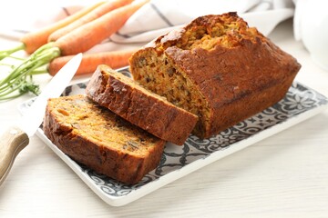Homemade carrot cake with nuts and vegetables on white wooden table, closeup