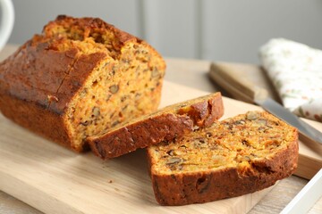 Cut homemade carrot cake with nuts and knife on table, closeup