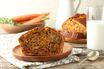 Homemade carrot cake with nuts, milk, vegetables and spoon on wooden table, closeup