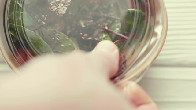 Closeup of man paking up a fresh healthy salad to a zero waste container to go. Food delivery, healthy food concept.