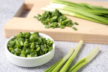 Whole and cut fresh green onions on light grey table, closeup